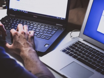 Egy személy laptopot és okostelefont használ egy világos szobában, szemléltetve a munka és a digitális hobbi közötti egyensúlyt.