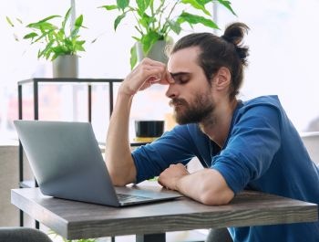 kimerült férfi az íróasztalnál, fáradtság okai és megoldások
