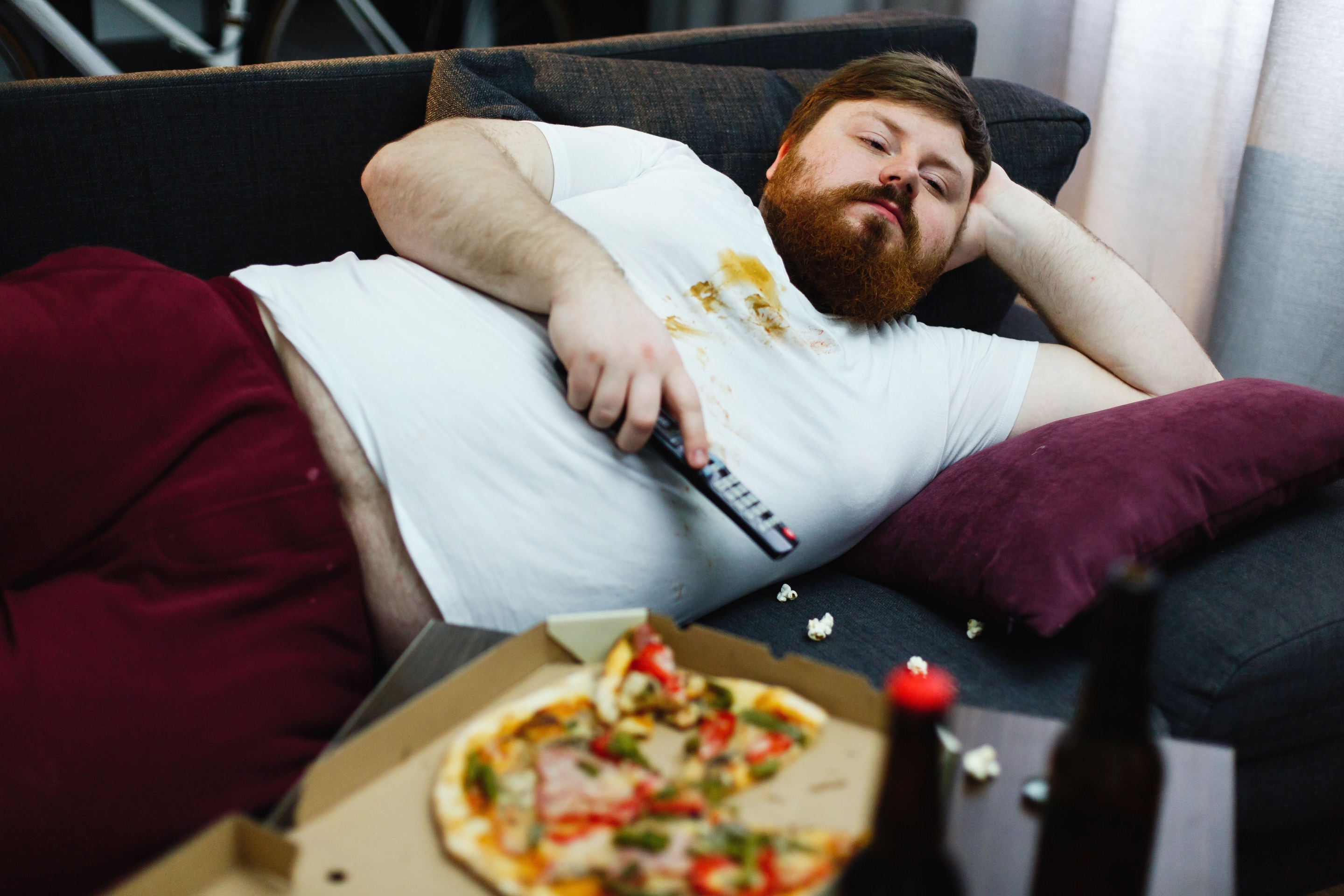 Неудачник просидевший. Толстый человек на диване. Толстый человек лежит на диване. Толстый ленивый человек. Лежание на диване с едой.